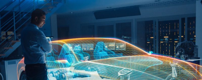 In Automotive Innovation Facility Automobile Design Engineer Working on 3D Holographic Model Projection of Electric Car. Futuristic Concept of Virtual and Augmented Realty Use.